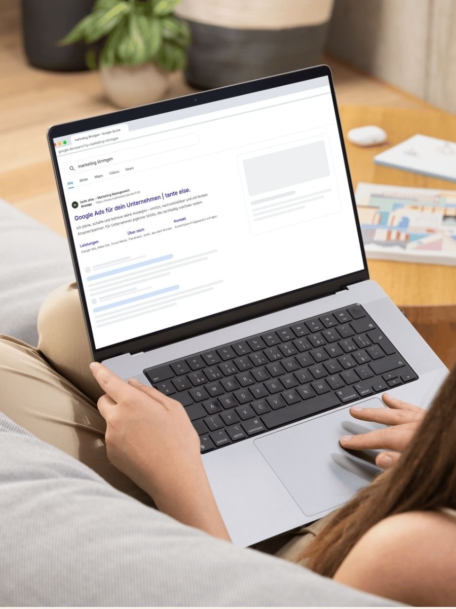 Frau sitzt mit dem Laptop auf dem Sofa, auf dem Bildschirm eine Google-Suchanzeige von tante else.